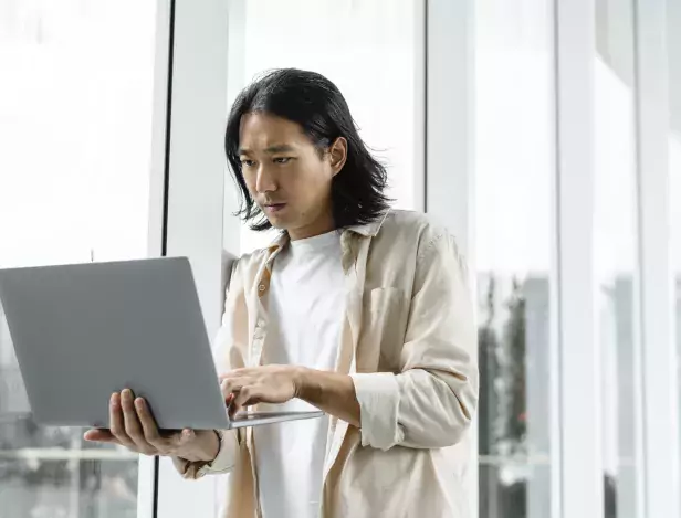 asian-man-using-laptop-while-out-about-city