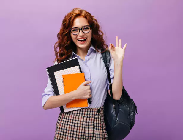 red-haired-lady-eyeglasses-holds-books-shows-ok-sign